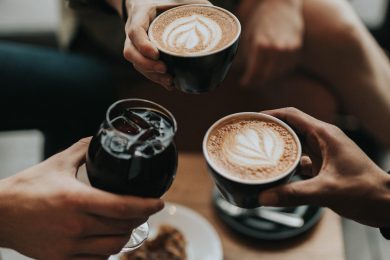 hands holding cups of coffee and juice